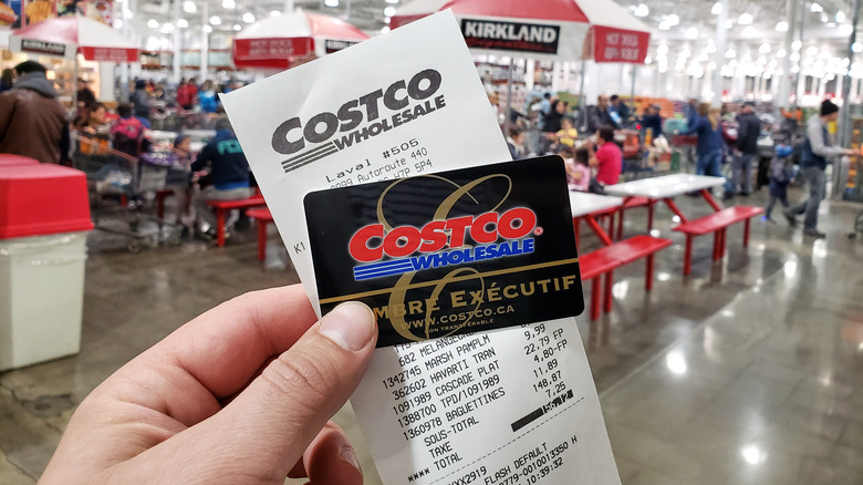 Holding Costco membership card next to cart