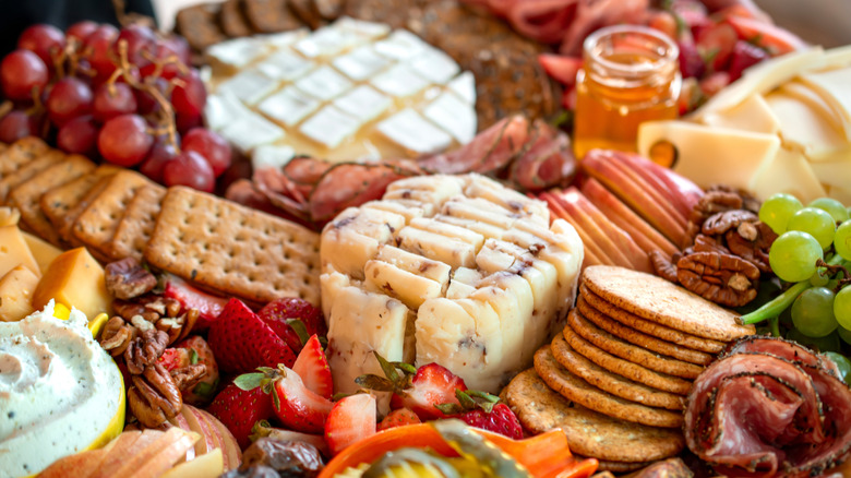 large, over-stuffed charcuterie spread with cheese, fruits, salumi, crackers, olives, and more