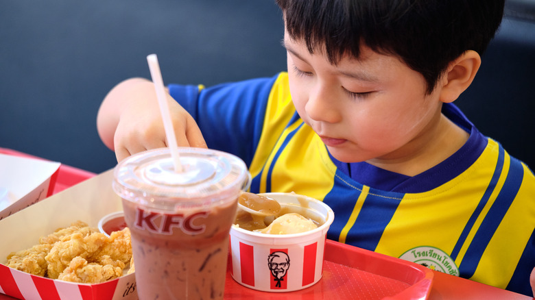 boy eats mashed potatoes from kfc