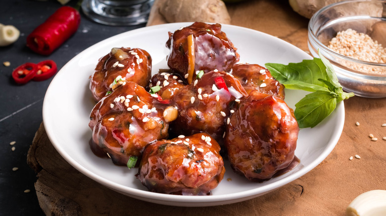 Meatballs coated with jelly on a white plate