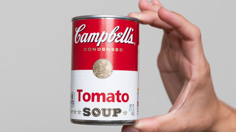 hand holding can of campbell's soup tomato soup