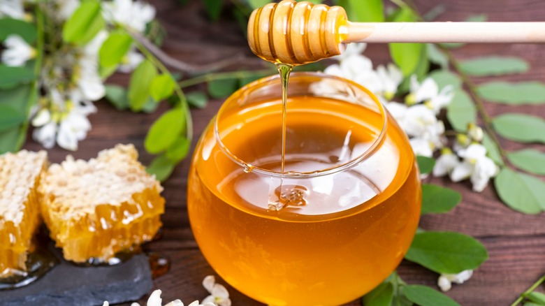 glass with honey and honeycombs beside it