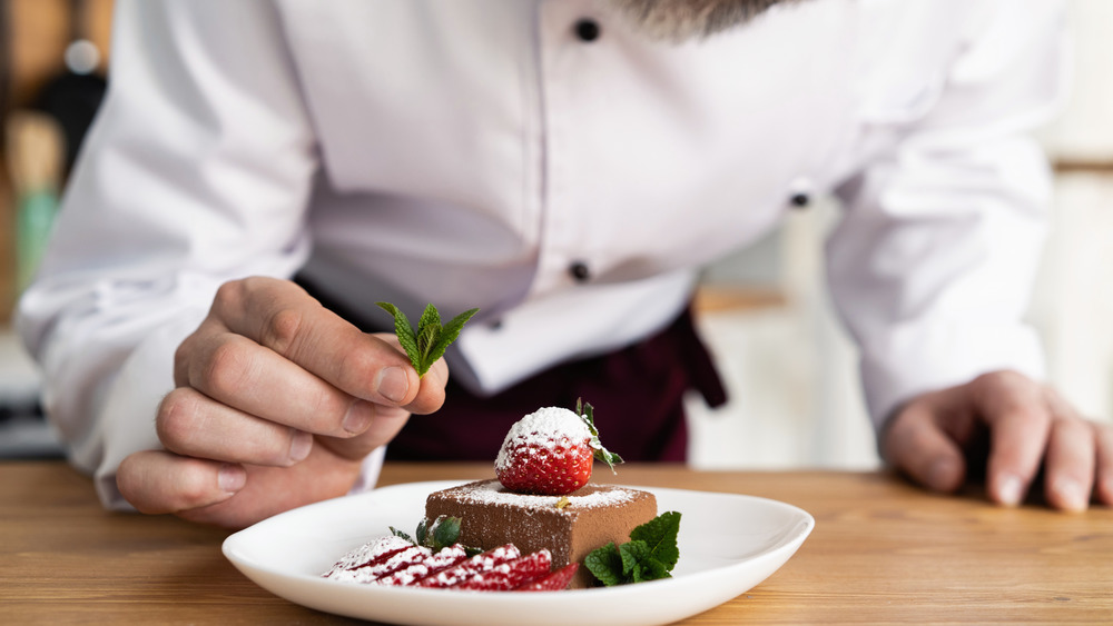 chef garnishing a plate of dessert