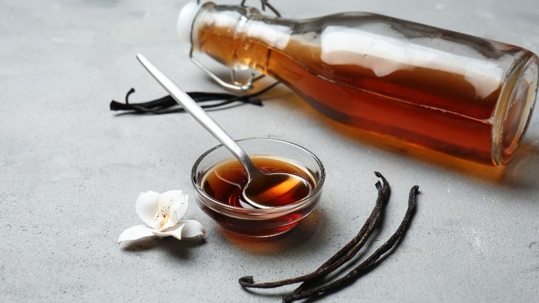 Vanilla extract in bowl and bottle with vanilla beans