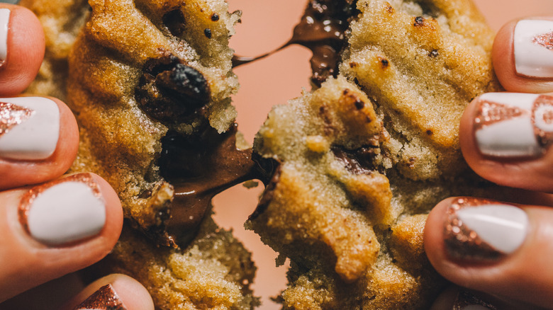 Hands pulling apart chocolate chip cookie