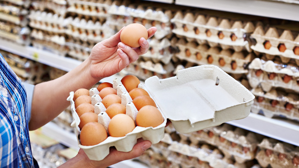 Person inspecting eggs in carton