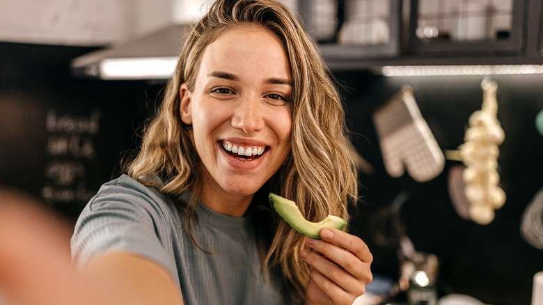 Woman eating a slice of avocado