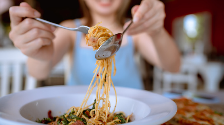 Person eating spaghetti with a spoon