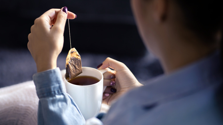 Woman pulling teabag from mug