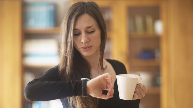 Person with mug checking watch