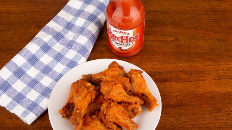 Plate of wings with a bottle of Frank's Red Hot Sauce