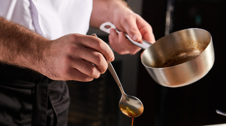 Person in white drizzling a sauce