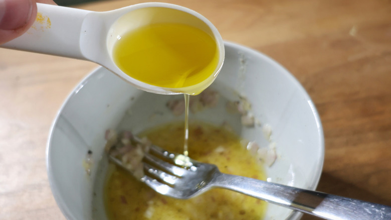 pouring thin stream of olive oil into bowl