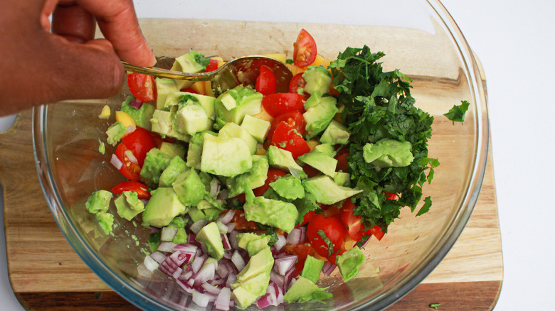 A hand mixing mango salsa together