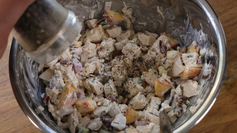 grinding pepper into chicken salad