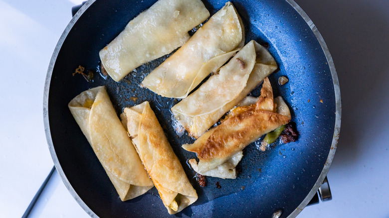 Taquitos frying in a skillet