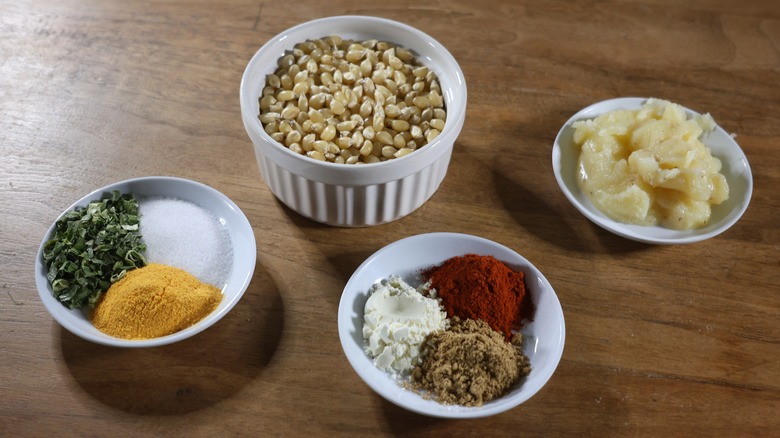 Frito pie popcorn ingredients in small dishes on wooden table