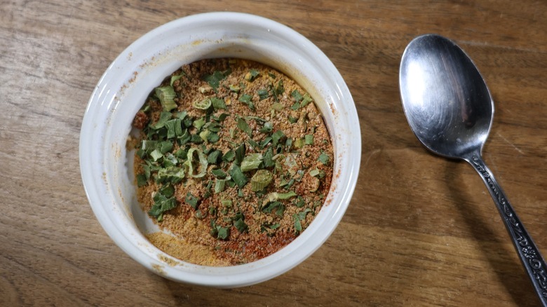 ramekin of seasoning mix with spoon beside it on wooden table