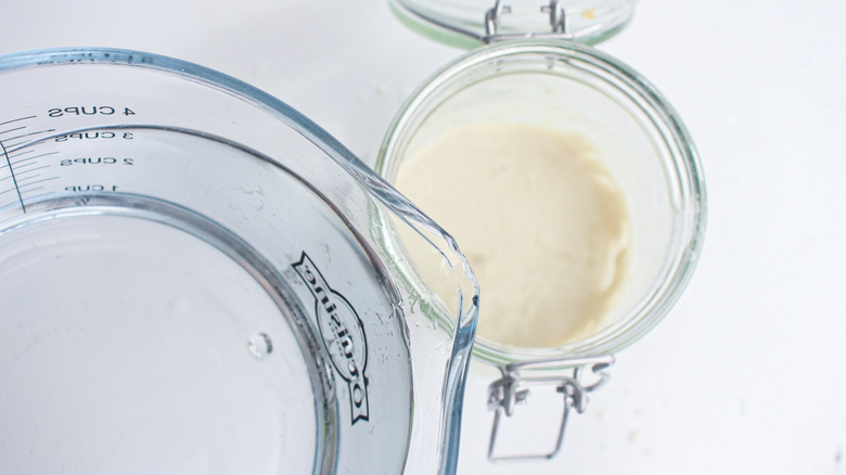 pouring water into sourdough starter