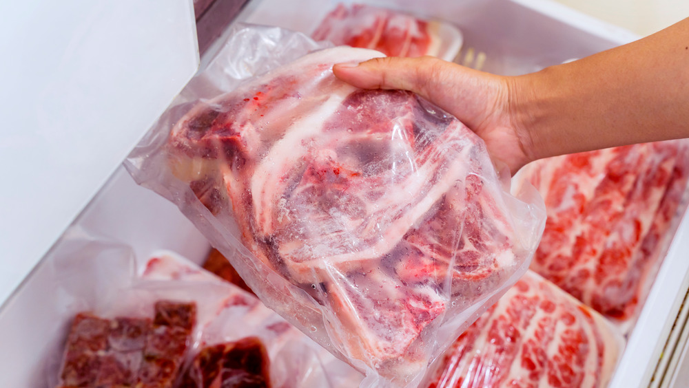 Hand selecting frozen meat from freezer