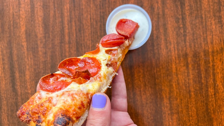 slice of pepperoni pizza being dipped in ranch