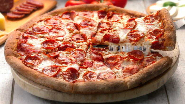 sliced pepperoni pizza being grabbed