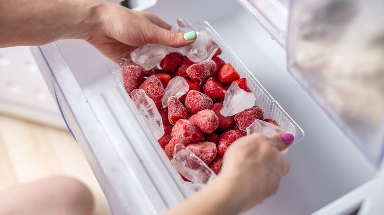 Frozen strawberries with ice in fridge 