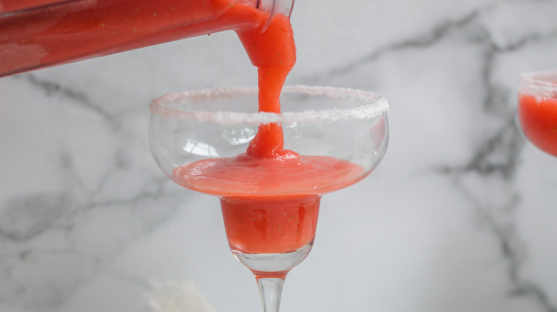 Frozen strawberry margaritas being poured out of the blender