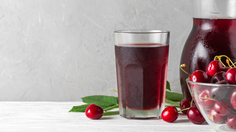 cherry juice pitcher and glass with a bowl of fresh cherries