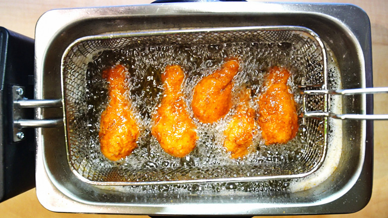 chicken frying in basket of fryer