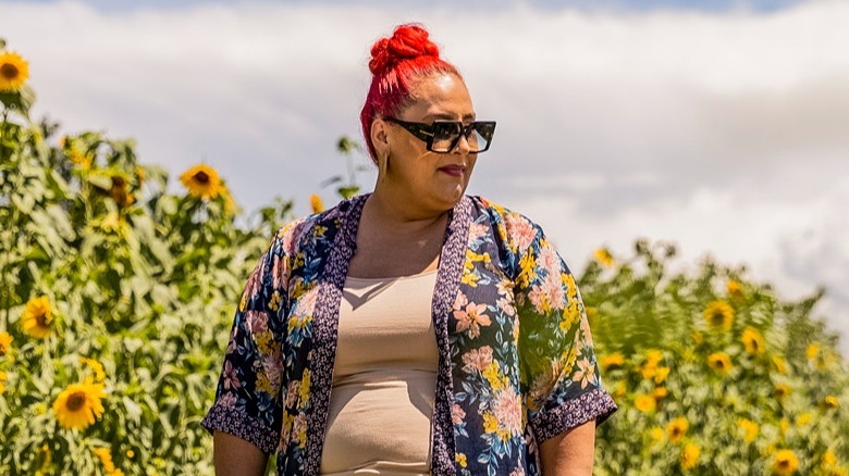 Claudia Sandoval standing in front of sunflowers