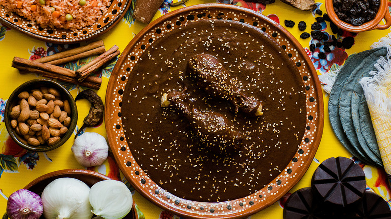 Mexican mole sauce in dish next to ingredients on table