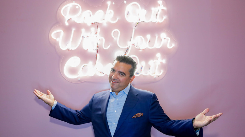 Buddy Valastro in front of a "Rock Out with Your Cake Out" neon sign