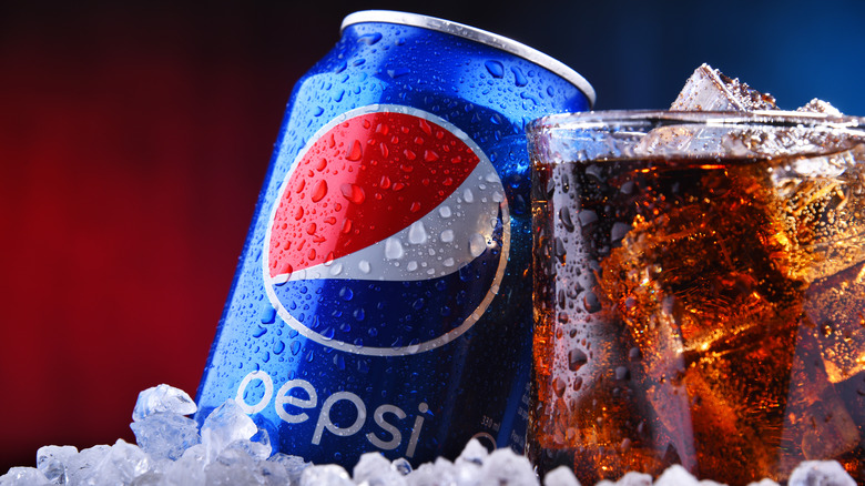 can of Pepsi next to a glass of the cola over ice