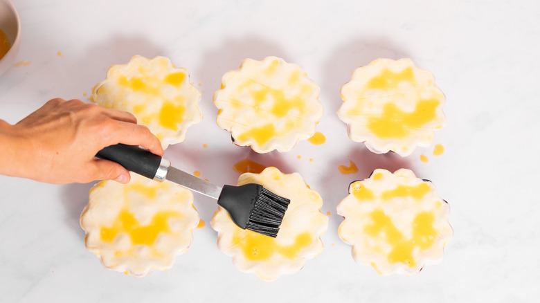 hand brushing pies with egg wash 