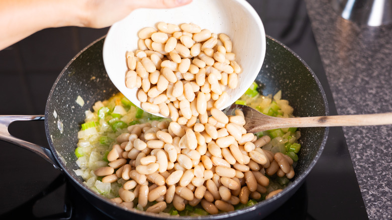 cannellini beans going into pan of vegetables