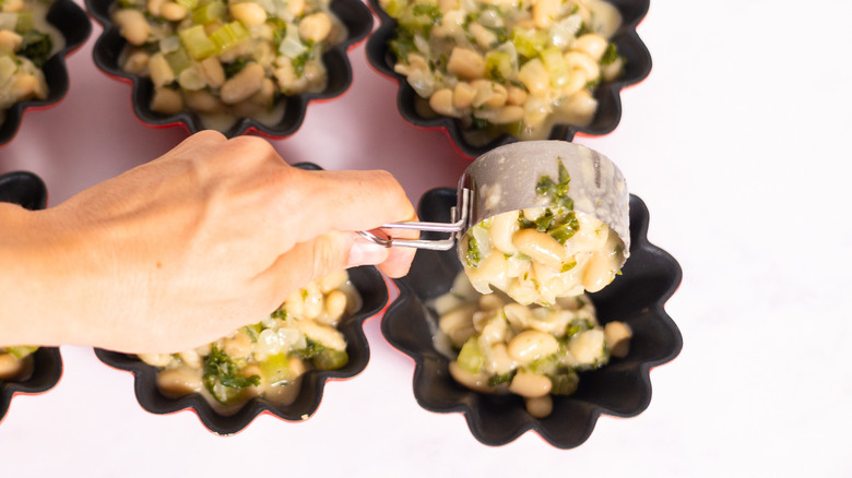 hand filling pie molds with cannellini bean mixture 