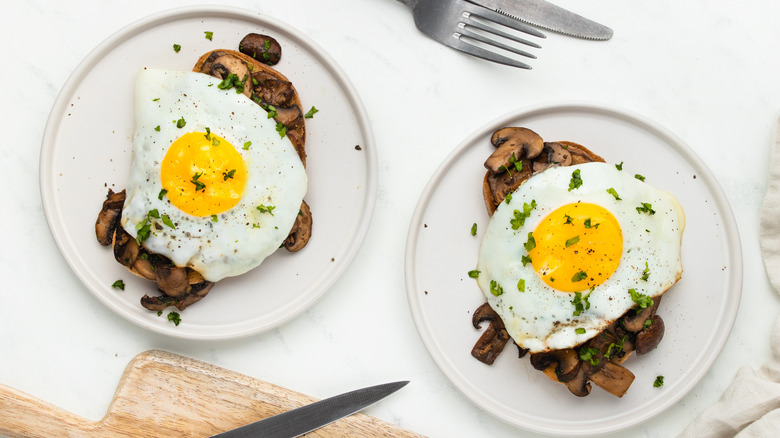 topping fried eggs on mushroom toast