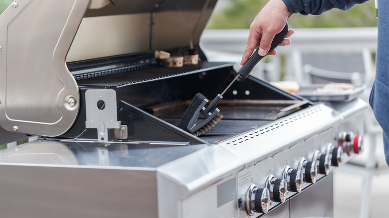 man cleaning gas grill