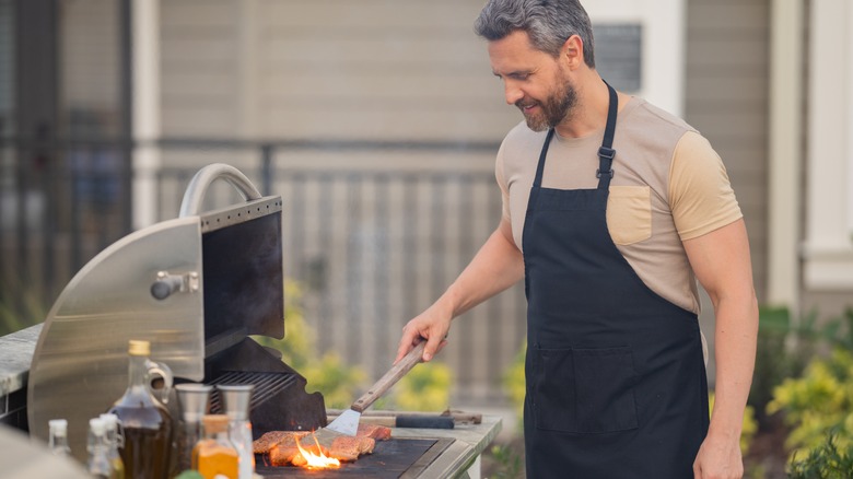 happy man cooking steak gas grill