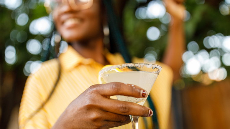 woman holds cocktail in martini glass