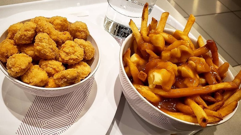 bowl of KFC poutine beside nuggets and a glass of water 