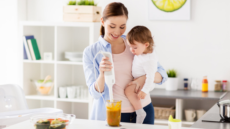 Mother holding baby making food