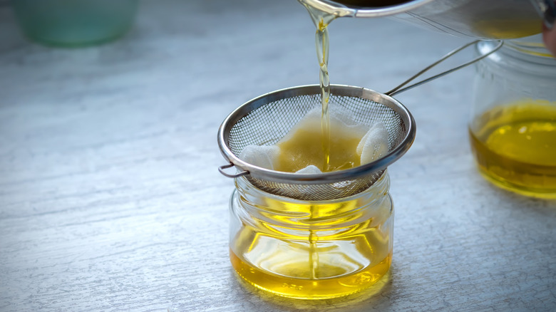 Ghee being strained into a glass jar