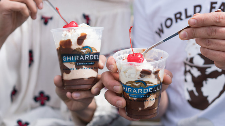 Two people eating Ghirardelli sundaes from plastic cups