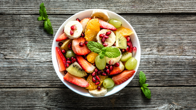 Fruit salad in white bowl on wooden surface