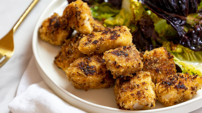 Breaded chicken tenders on plate with salad.