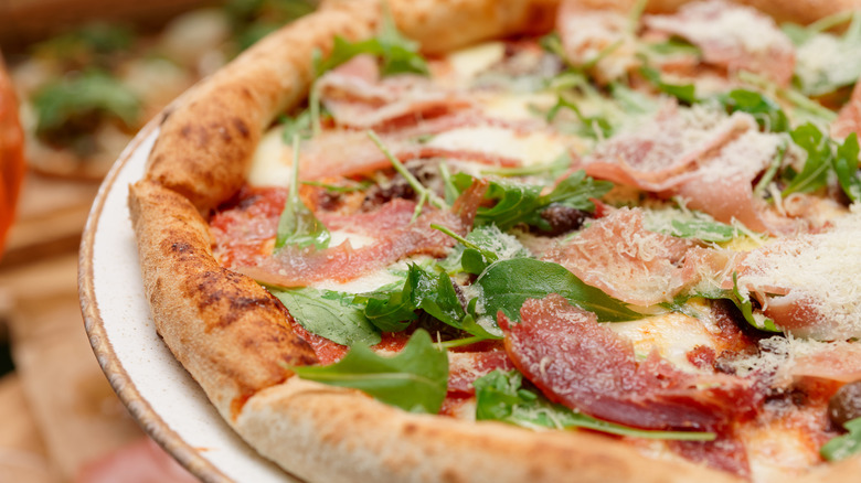 A pizza with prosciutto and arugula