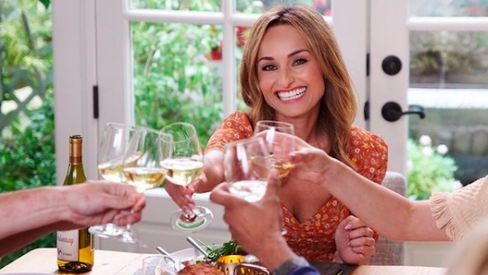 Giada De Laurentiis toasts wine at dinner table