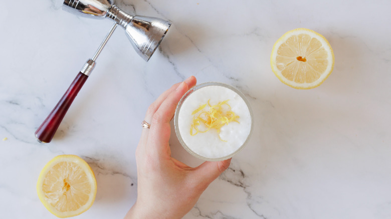 hand serving drink with lemon halves around